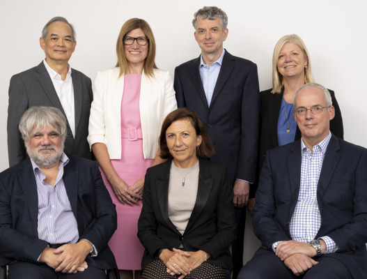 Seven people in business clothing; four men and three women