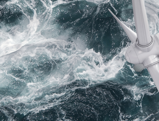 Overhead view of offshore wind turbine with waves crashing around
