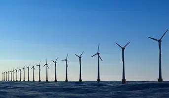 A line of offshore wind turbines with blue skies
